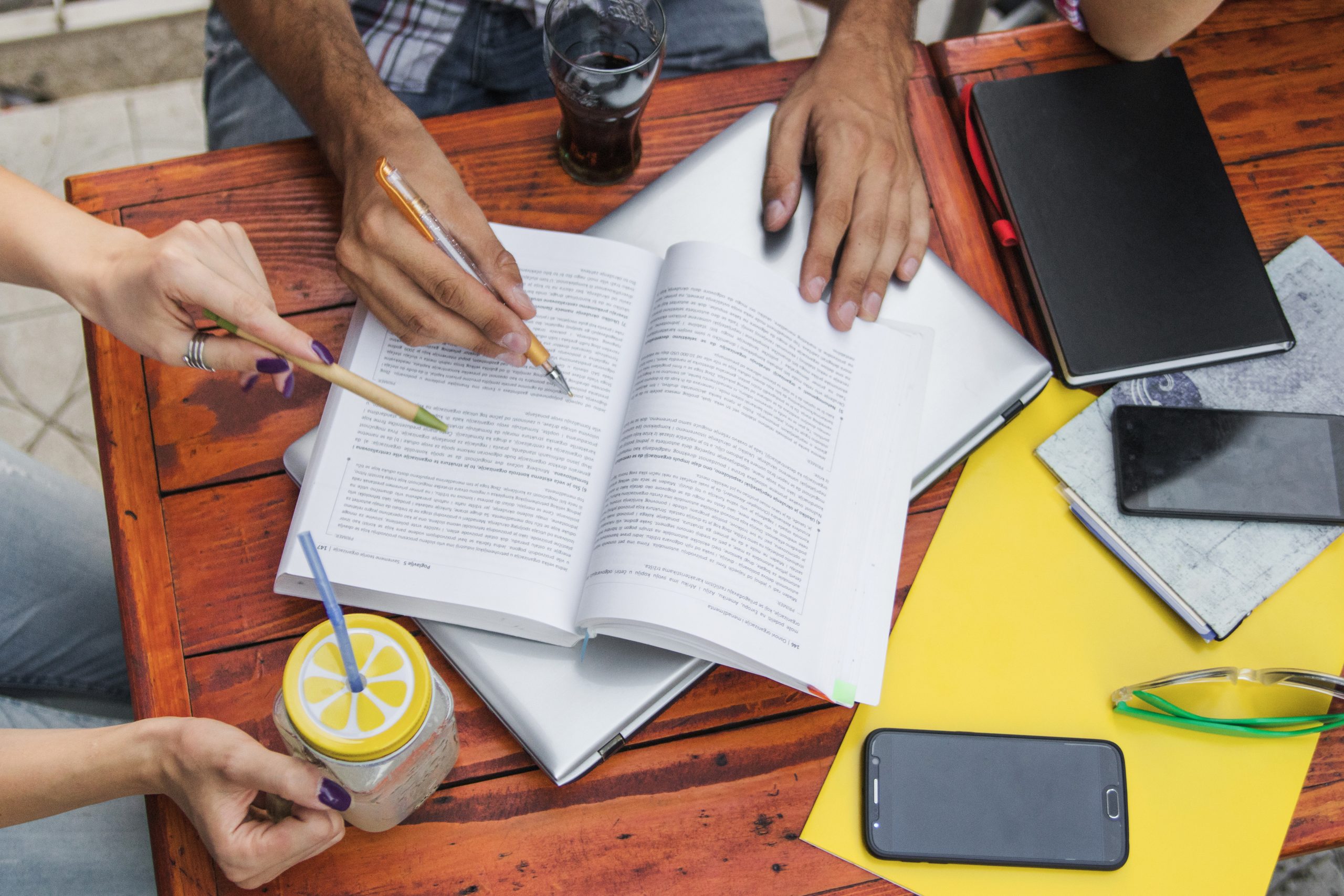 An organized desk with academic papers sorted into themes, and a scholar using a mind map on a screen to connect ideas for a literature review