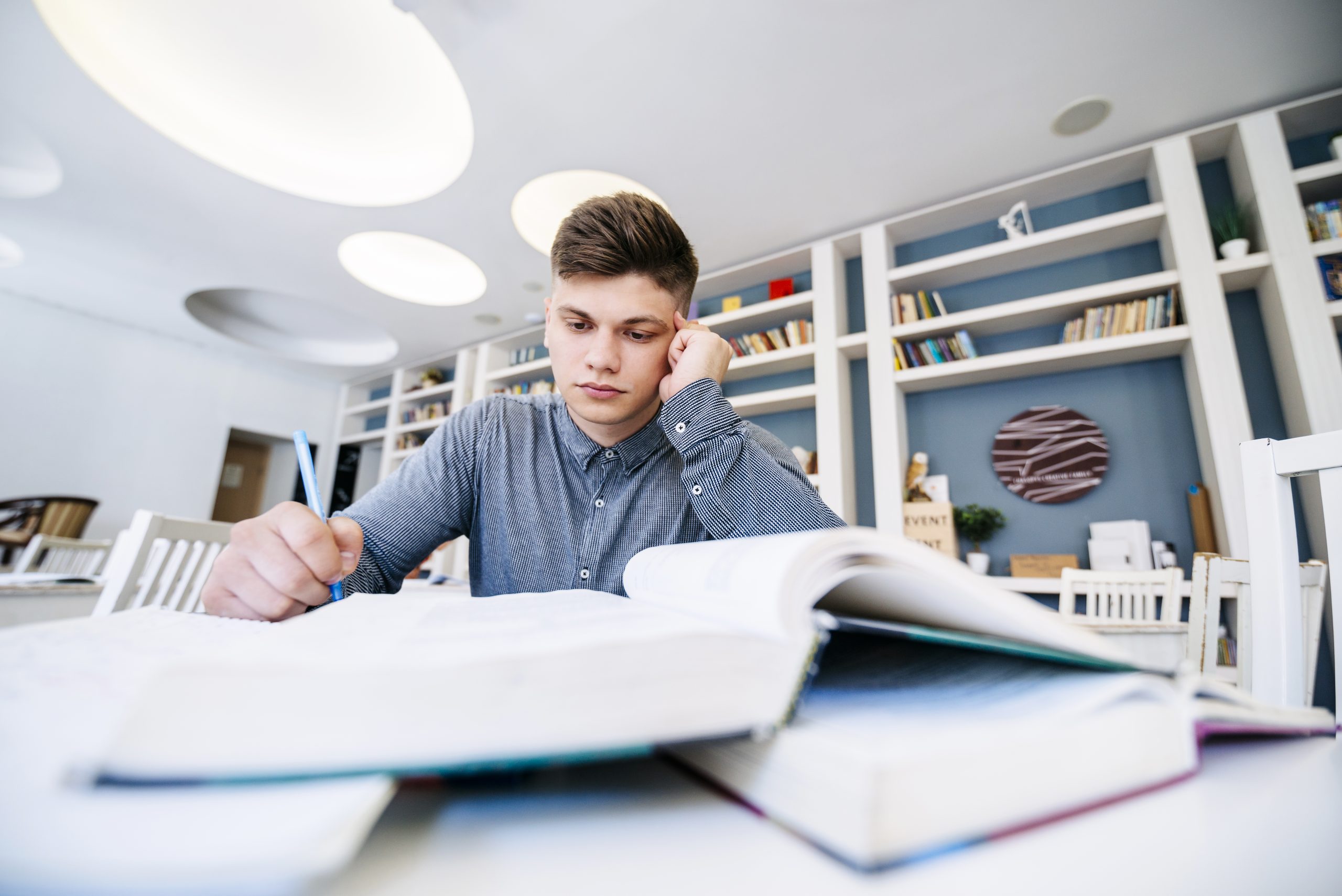 A PhD student organizing color-coded sticky notes and research papers on a large desk, planning the structure of their thesis.